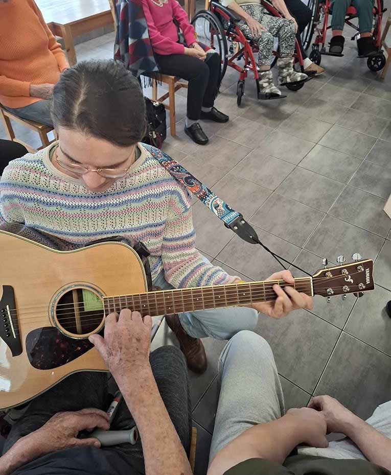 Seniorzy w Rytmie prezentują gitarę pacjentce